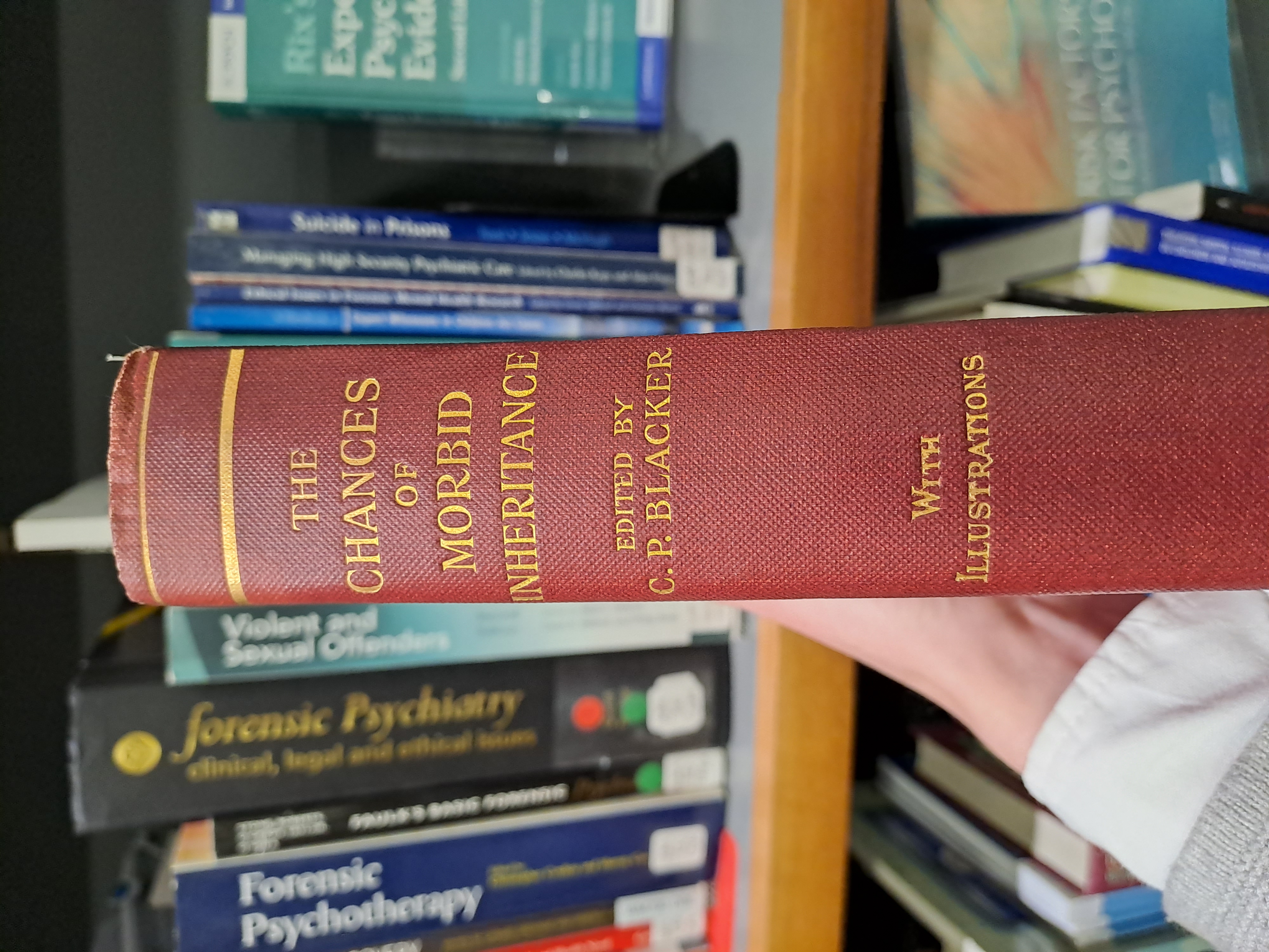 Spine of a red book with gold lettering reading 'the chances of morbid inheritance, edited by CP BLacker, with illustrations '