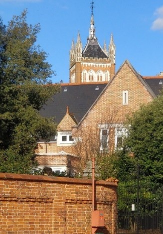 Fancy Victorian building in pale brick with ornate tower.
