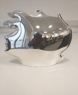 Silver sculpture shaped like a highly stylised head in portrait