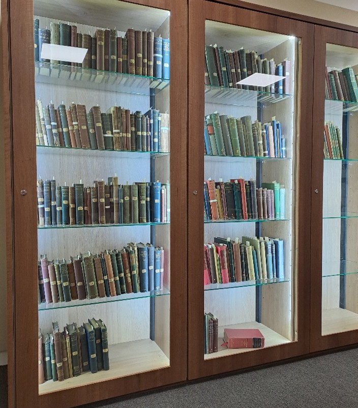 Glass and wood cabinet full of old books