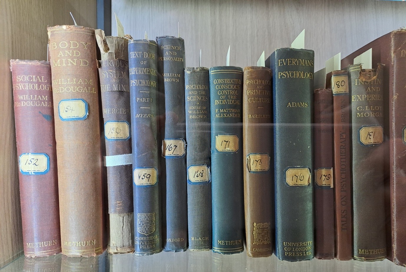 Row of old books in a glass cabinet.