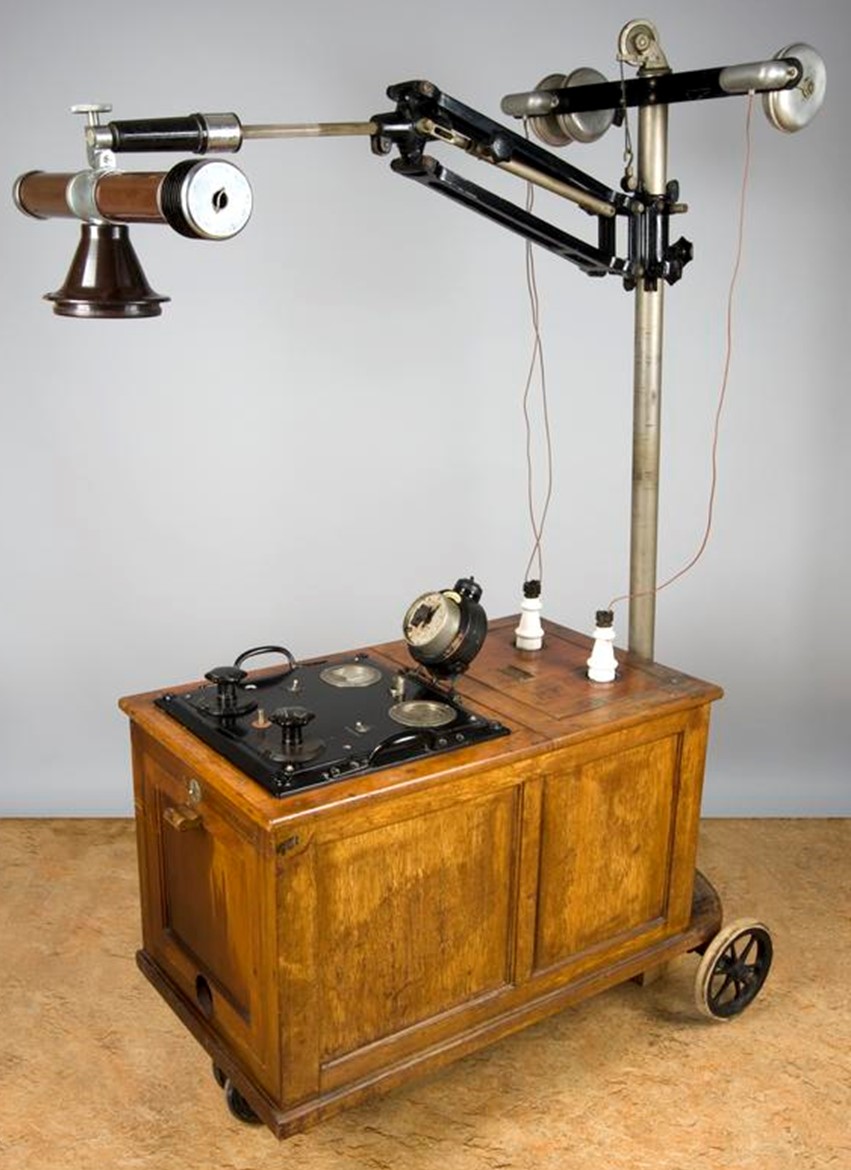 Wooden box on wheels with metal crane like appendage.