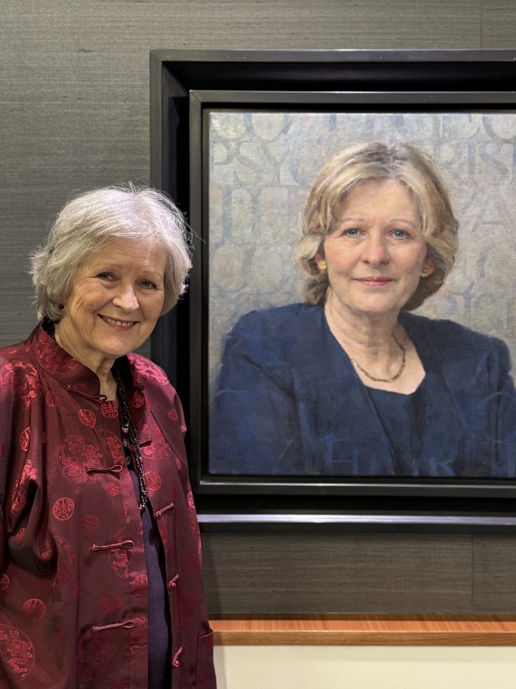 Baroness Sheila Hollins standing next to her portrait