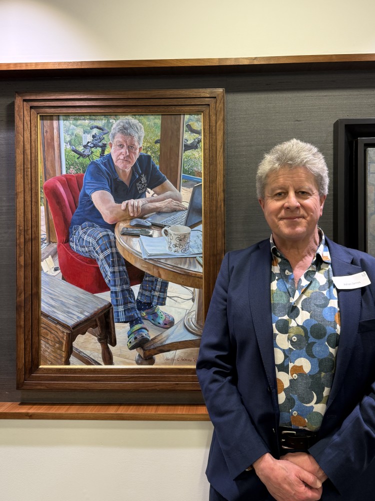 Dr Adrian James standing next to his portrait