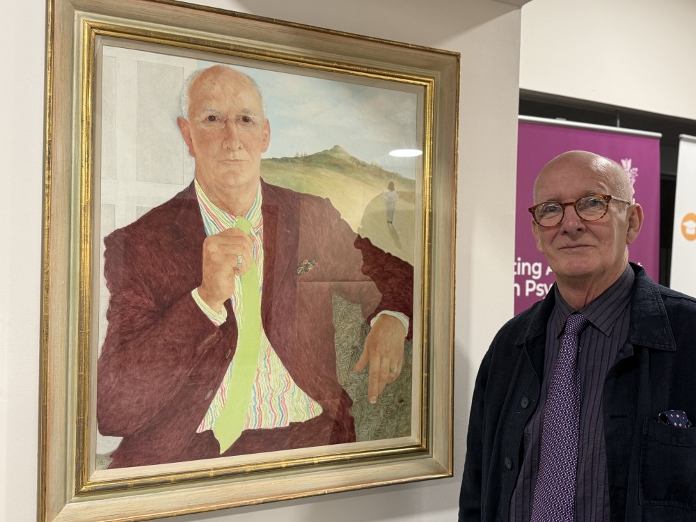 Dr Mike Shooter standing next to his portrait