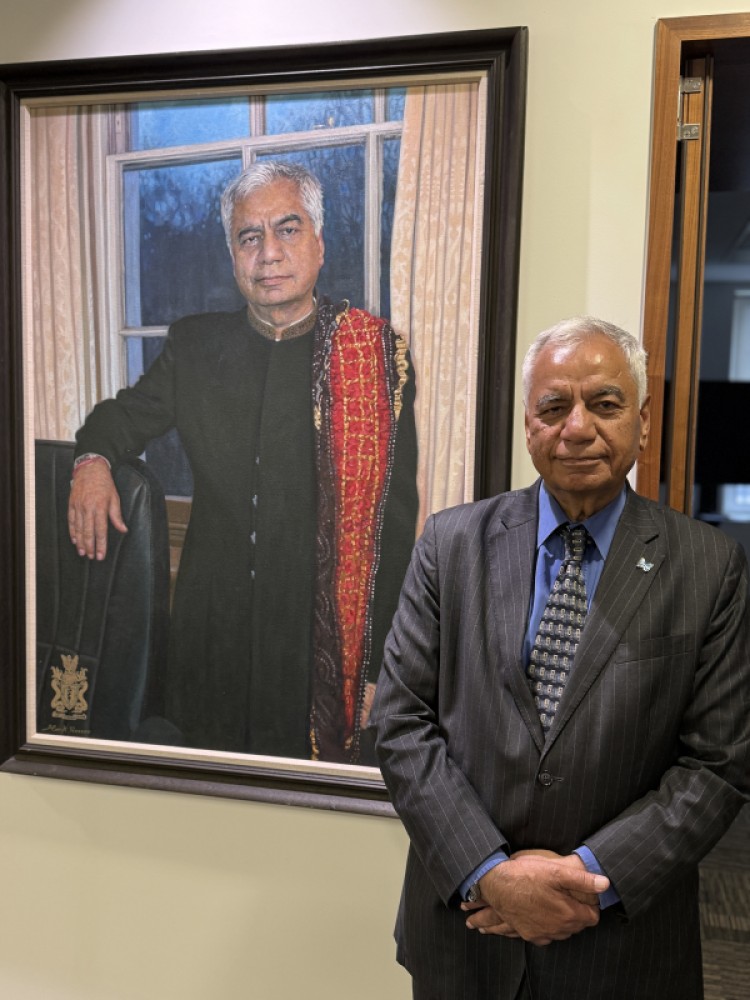 Professor Dinesh Bhugra standing next to his portrait